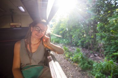 Sri Lanka 'nın dağlık bölgelerindeki çay tarlaları arasında Ella' dan Kandy 'ye tren yolculuğunun tadını çıkaran genç bir kadın.