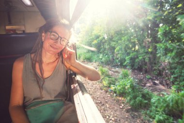 Sri Lanka 'nın dağlık bölgelerindeki çay tarlaları arasında Ella' dan Kandy 'ye tren yolculuğunun tadını çıkaran genç bir kadın.