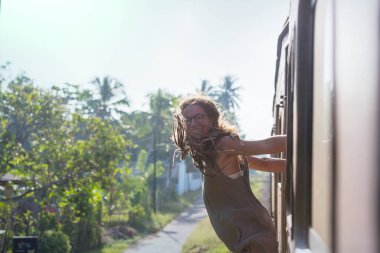 Sri Lanka 'nın dağlık bölgelerindeki çay tarlaları arasında Ella' dan Kandy 'ye tren yolculuğunun tadını çıkaran genç bir kadın.