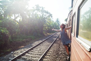 Sri Lanka 'nın dağlık bölgelerindeki çay tarlaları arasında Ella' dan Kandy 'ye tren yolculuğunun tadını çıkaran genç bir kadın.