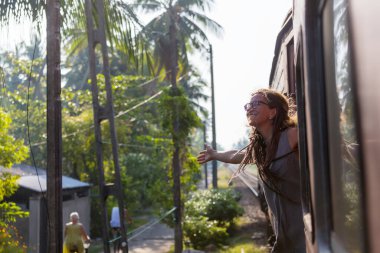 Sri Lanka 'nın dağlık bölgelerindeki çay tarlaları arasında Ella' dan Kandy 'ye tren yolculuğunun tadını çıkaran genç bir kadın.