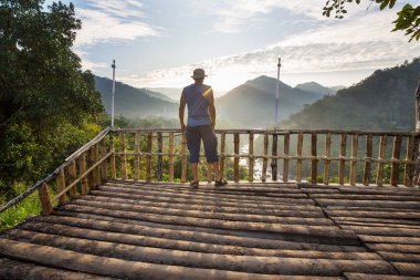 Bir turist, dağlık arazileri gözetliyor.
