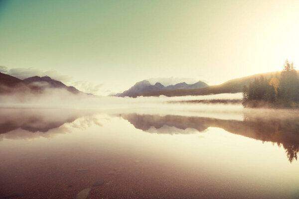Туманное горное озеро ранним утром в горах.