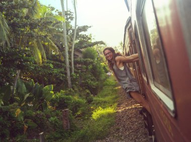 Sri Lanka 'nın dağlık bölgelerindeki çay tarlaları arasında Ella' dan Kandy 'ye tren yolculuğunun tadını çıkaran genç bir kadın.