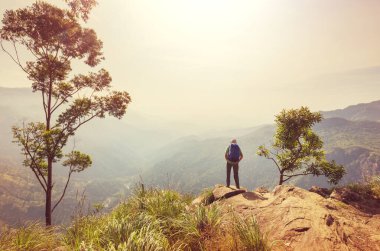 Bir turist, dağlık arazileri gözetliyor.