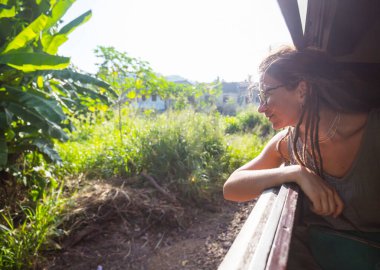 Sri Lanka 'nın dağlık bölgelerindeki çay tarlaları arasında Ella' dan Kandy 'ye tren yolculuğunun tadını çıkaran genç bir kadın.