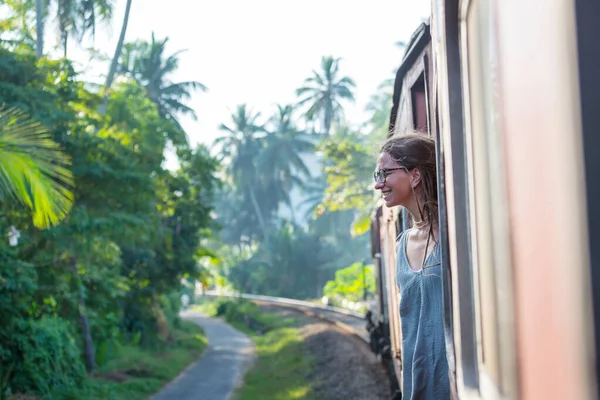 Sri Lanka 'nın dağlık bölgelerindeki çay tarlaları arasında Ella' dan Kandy 'ye tren yolculuğunun tadını çıkaran genç bir kadın.