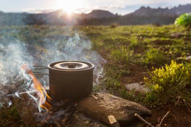 Yürüyüş sırasında kamp ateşinde yanan turistik çaydanlık. Ormanda odun üzerinde yemek pişirmek..