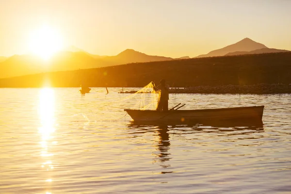 日出时坐在湖上的船夫 — 图库照片