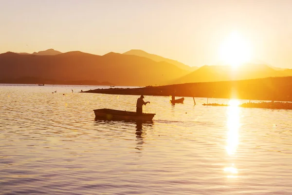 日出时坐在湖上的船夫 — 图库照片