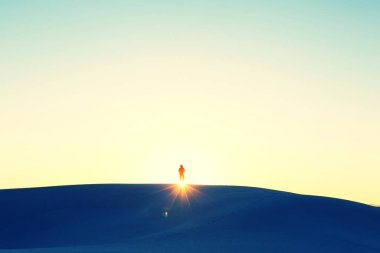 Kum çölünde bir yürüyüşçü. Gün doğumu zamanı.