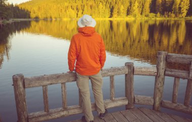 Bir adam sakin gölün yanında dinleniyor. Rahatlama tatili