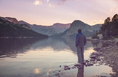 Bir adam sakin gölün yanında dinleniyor. Rahatlama tatili