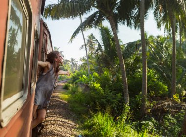 Sri Lanka 'nın dağlık bölgelerindeki çay tarlaları arasında Ella' dan Kandy 'ye tren yolculuğunun tadını çıkaran genç bir kadın.
