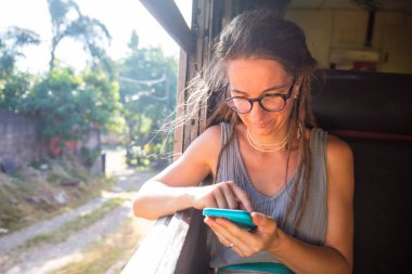 Sri Lanka 'nın dağlık bölgelerindeki çay tarlaları arasında Ella' dan Kandy 'ye tren yolculuğunun tadını çıkaran genç bir kadın.