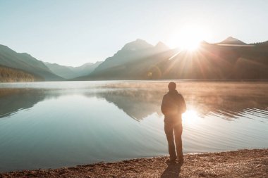 Bir adam sakin gölün yanında dinleniyor. Rahatlama tatili