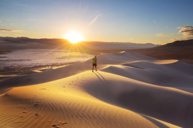 Çöldeki kum tepelerinin arasında bir yürüyüşçü