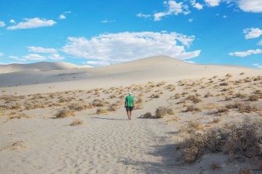 Çöldeki kum tepelerinin arasında bir yürüyüşçü