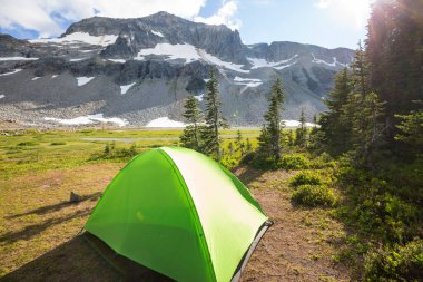 Yaz mevsiminde dağlarda kamp yaparken çadır ve kamp ateşi.