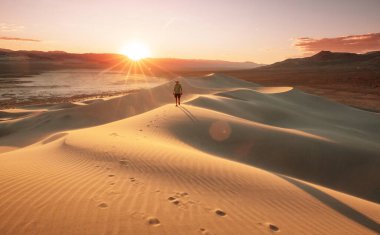 Kum çölünde bir yürüyüşçü. Gün doğumu zamanı.