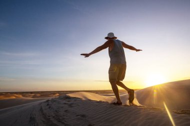 Brezilya 'nın Lencois Maranhenses Ulusal Parkı' ndaki gölcükler arasında gezen bir yürüyüşçü. Alışılmadık doğal manzaralar.