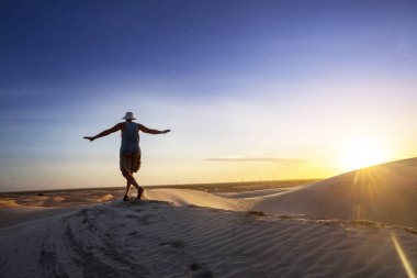 Brezilya 'nın Lencois Maranhenses Ulusal Parkı' ndaki gölcükler arasında gezen bir yürüyüşçü. Alışılmadık doğal manzaralar.