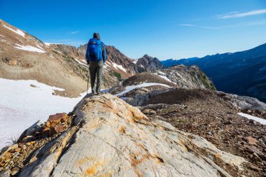 Yeşil tepelerde yürüyüş yapan biri.