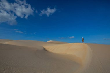 Çöldeki kum tepelerinin arasında bir yürüyüşçü