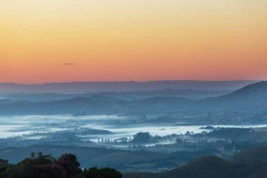 Güneşin doğuşunda puslu kırsal vadi.