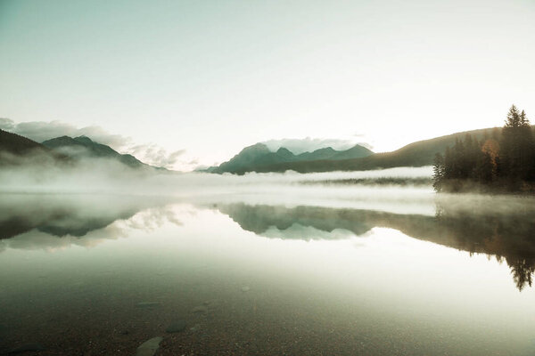 Туманное горное озеро ранним утром в горах.