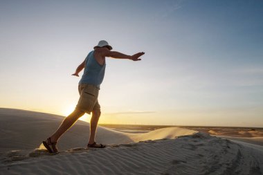 Çöldeki kum tepelerinin arasında bir yürüyüşçü