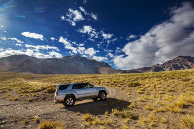 Gün doğumunda yüksek dağlarda karadan gelen bir araba.