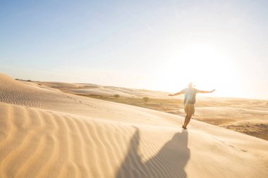 Çöldeki kum tepelerinin arasında bir yürüyüşçü