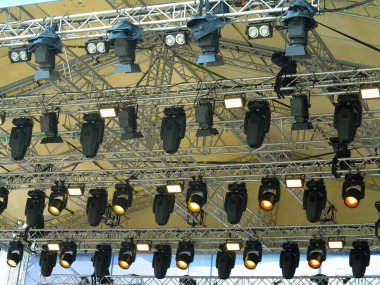 Spotlight devices in a row on  rigging steel trusses, installation of professional stage concert equipment.