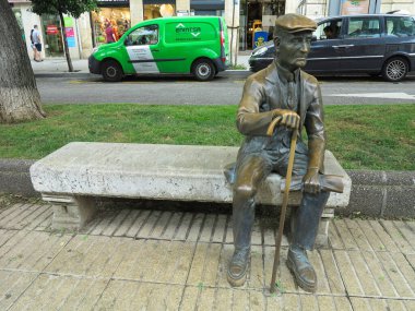 TARRAGONA, SPAIN- 06.07.2022: Monument to a pensioner grandfather sitting on bench statue at Rambla street