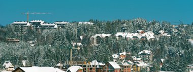 İnşaat endüstrisi apartmanı ve Zlatibor 'daki konut geliştirmesi kış mevsiminde kar altında, bina ve vinçler çam ormanlarını ele geçiriyor.