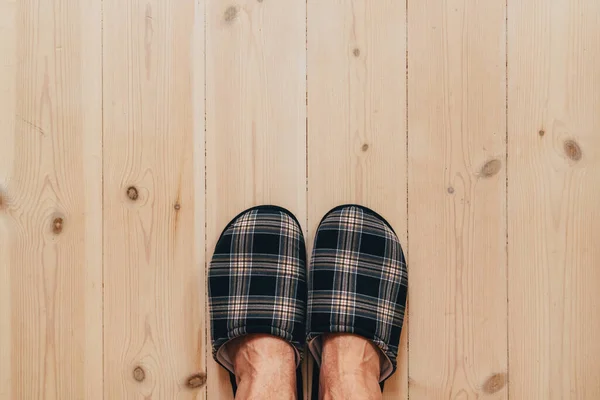 ホームスリッパを着用し リビングルームの堅木張りの床に立つ男性の足のトップビュー コピースペースが含まれています — ストック写真