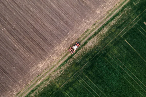 带有作物播种机的农业拖拉机的空中射击 沿着土路穿过犁地 无人驾驶飞机在正上方 — 图库照片