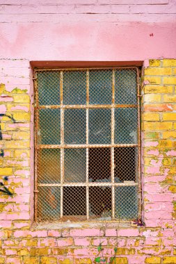 Eski bir fabrika deposunun dış duvarında kırık camlar olan eski şebeke pencereleri.