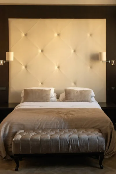 Hotel room bedroom furniture - a bed with headboard, pillows and bedside lamps