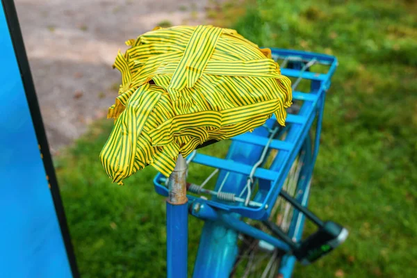 Damaged bicycle seat taped with green and yellow electrical duct tape, selective focus