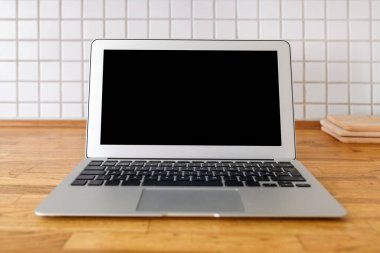 Laptop computer with blank mockup screen on kitchen counter, selective focus