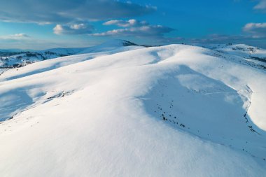 Sırbistan 'ın Zlatibor kentinde kış günbatımında batan güneşle aydınlanan karlı tepenin hava görüntüsü insansız hava aracı pov' undan.