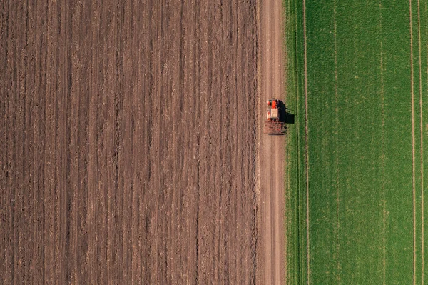 現場作業後の未舗装道路を走行するタイヤ付き農業用トラクターの空中図 — ストック写真