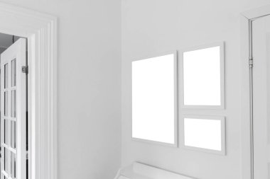 Three white wooden picture frames with mockup space for photography hanging on living room wall, selective focus