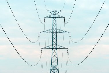 Energy crisis concept, electricity pylon with overhead powerline cables against overcast sky