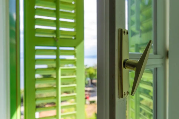 Open window with green wooden shutters with view of the Lovran, travel destination at Istrian seaside in Croatia, selective focus