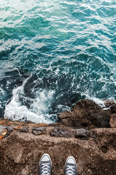 岩で波がクラッシュした後 冷たい水と海の泡の上の海の崖に立って自殺のアイデアや考え 若い人 Pov画像 — ストック写真