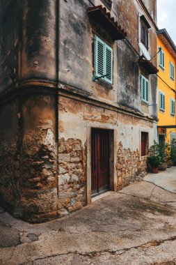 Old town of Lovran in Croatia, distinctive Istrian architecture with worn facades and wooden window shutters, selective focus