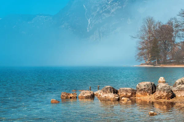 안개가물 표면을 호수의 커다란 바위들 배경에 율리아 알프스 가선택적으로 집중하고 — 스톡 사진